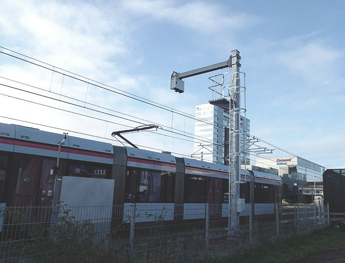 PanMon pantograph monitoring mounted above railway catenary cables looking down on a train with a pantograph