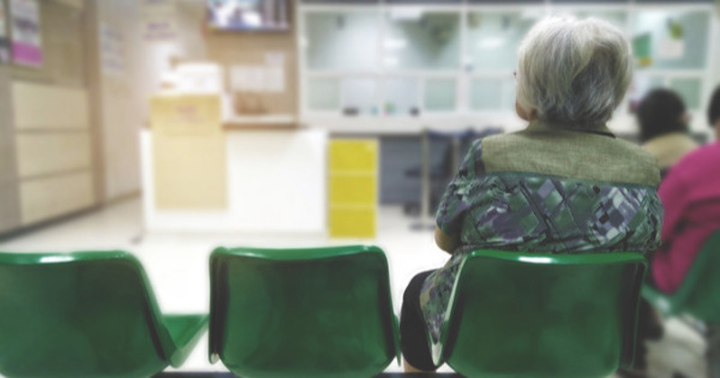 A person sat on green chairs in a hospital waiting room