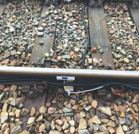 Image of a rail with a sensor attached and wires coming from it.