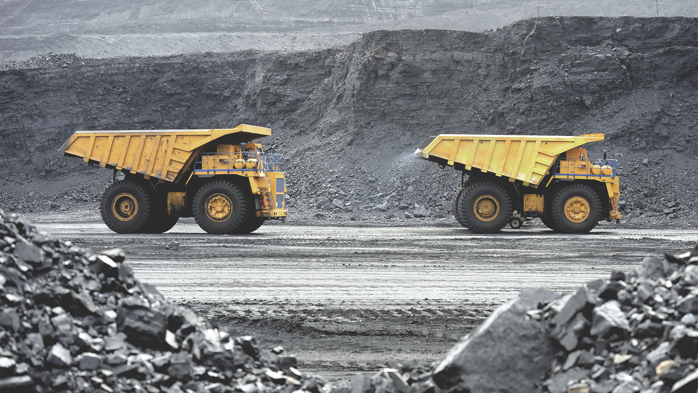 Yellow dump trucks driving through a mined quarry