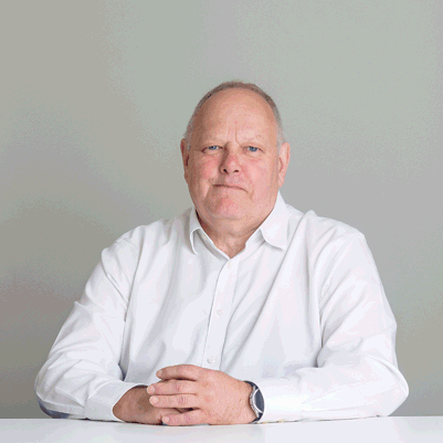 Tony Golland sitting at a table against a grey background